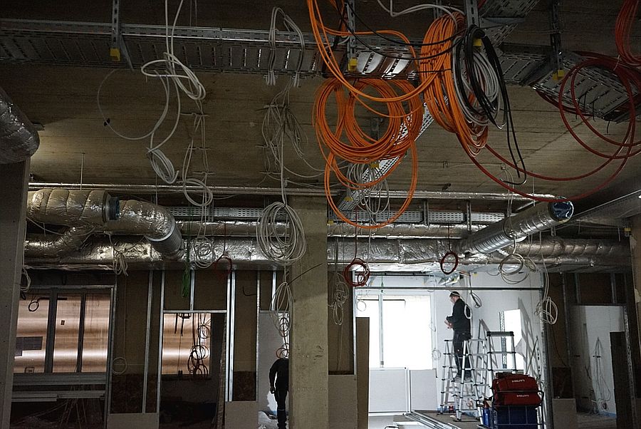 Innere vom Neubau mit hängenden Stromleitungen und Klimaleitungen