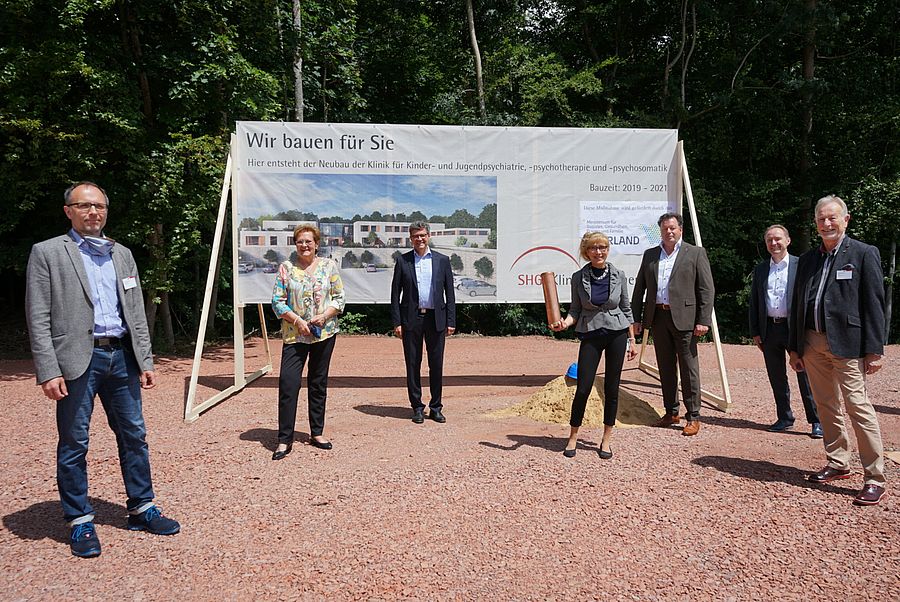 Sieben Personen stehen vor Informationstafel zu Bauarbeiten