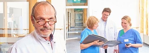 Prof Dr med Matthias Strittmatter schaut in die Kamera und Team im Hintergrund