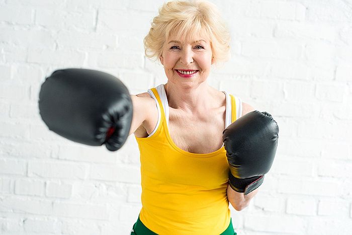 Ältere Dame mit Boxhandschuhen demonstriert ihre Fitness