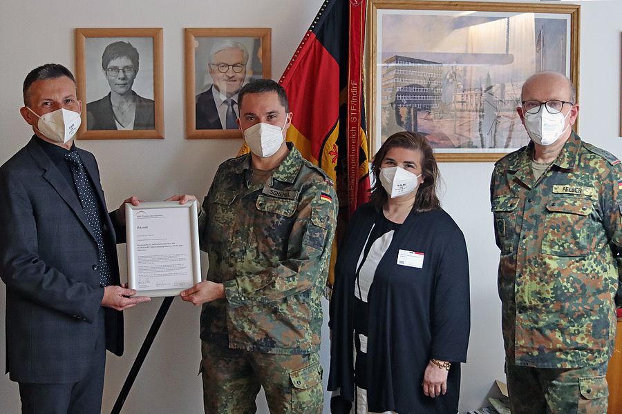 Verwaltungsdirektor übergibt Urkunde an Soldaten