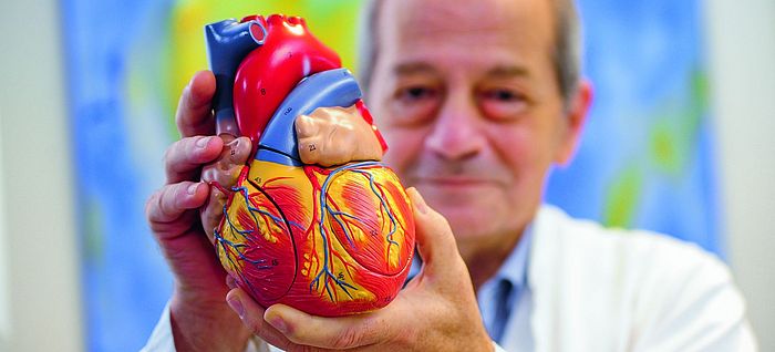 Dr med Cem Özbek hält das Modell eines Herzens in die Kamera