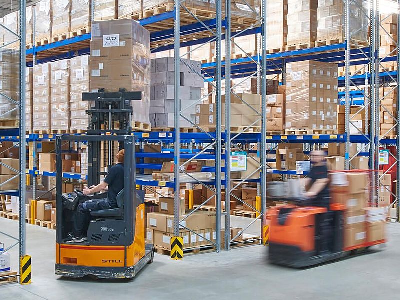 Mitarbeiter fahren mit Gabelstapler durch Lagerhalle