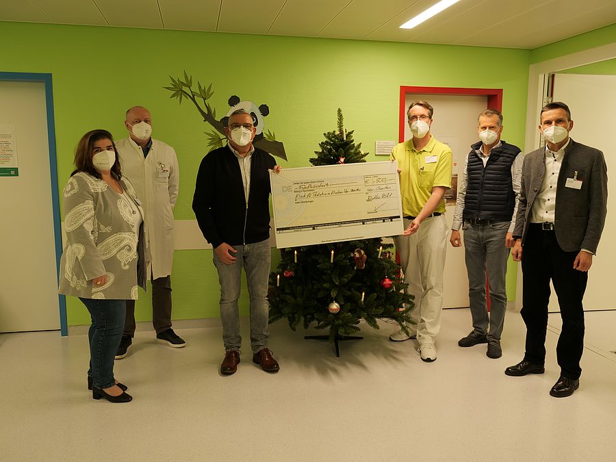 Stefan Dreher und Chefarzt der Kinderklinik halten Scheck