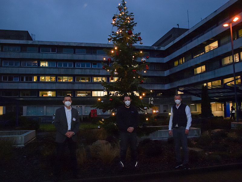 Verwaltungsdirektor Hendrik Weinz Firmen-Geschäftsführer Daniel Reis und Ärztlicher Direktor Dr med Ulrich Frey vor dem großen Weihnachtsbaum auf dem Vorplatz des Klinikums