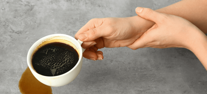 Hände halten verschüttete Kaffeetasse